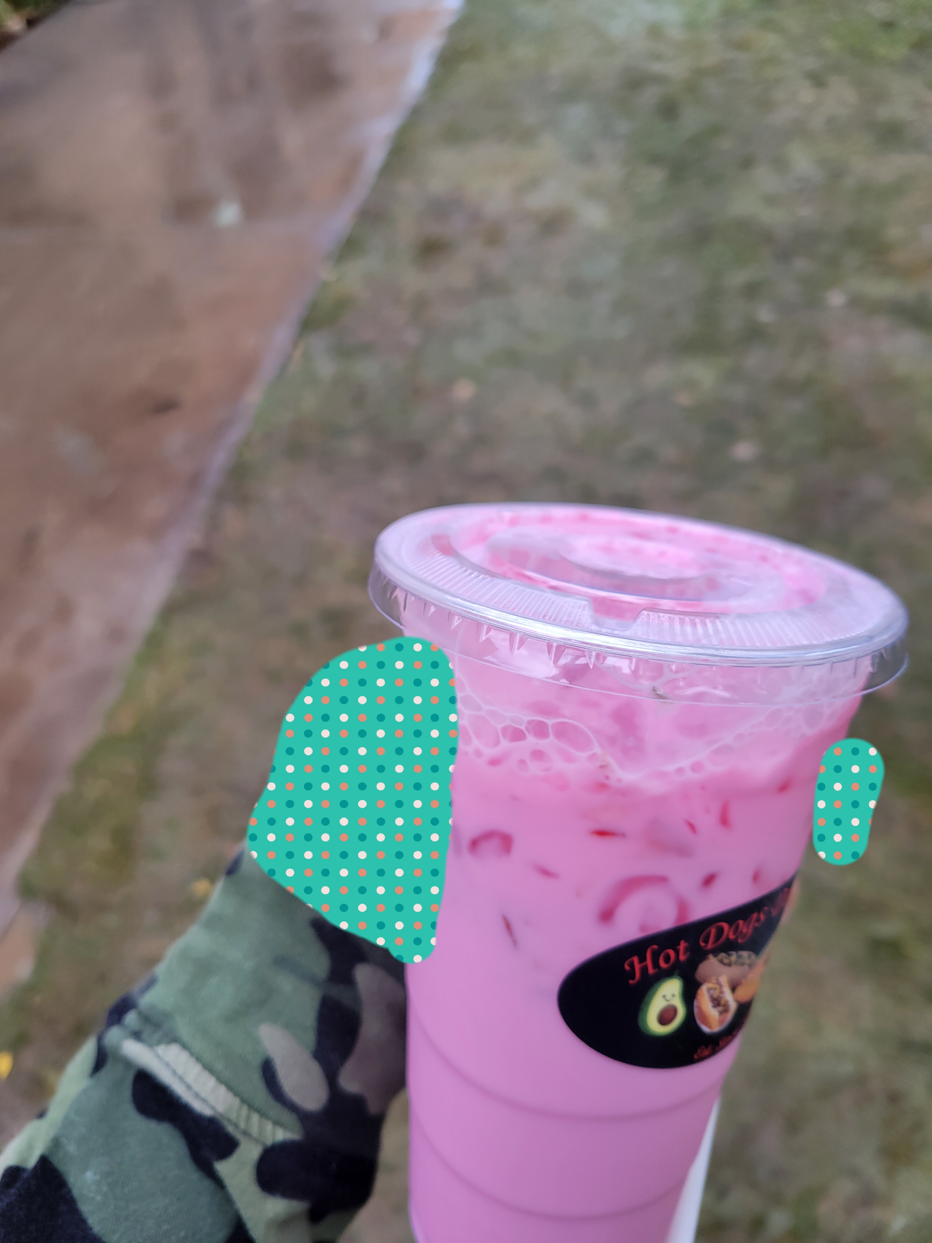 Hand holds plastic cup filled with strawberry horchata.